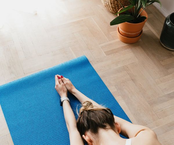 A comfortable home corner with a yoga mat and a plant.